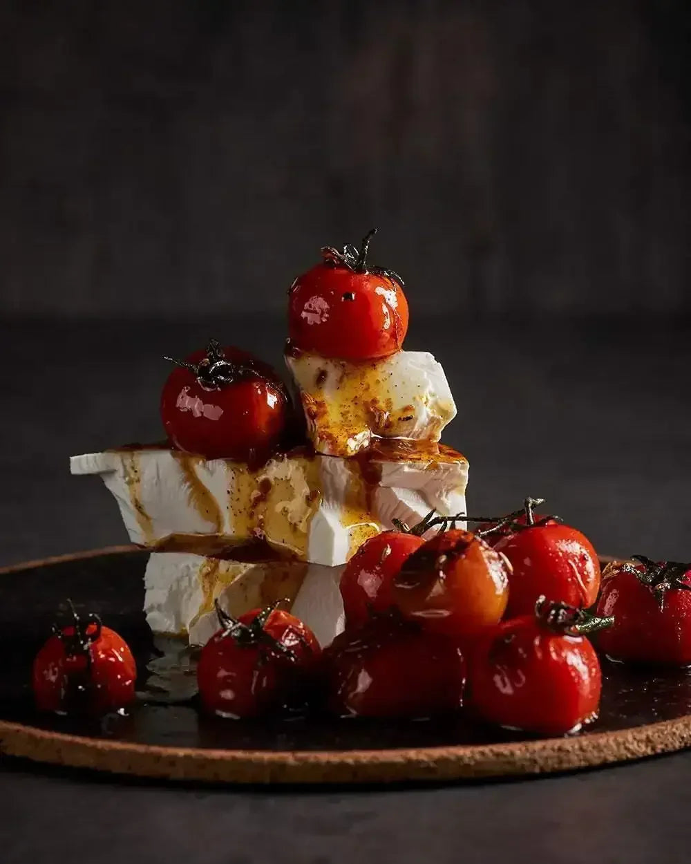 Fresh roasted cherry tomatoes stacked on creamy feta cheese, drizzled with balsamic glaze
