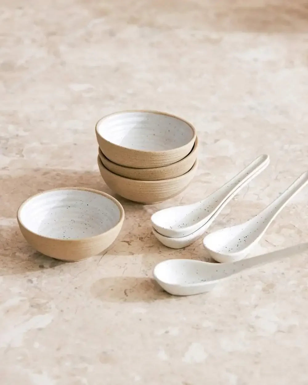 Ceramic mini bowl and spoon set with natural speckled finish on marbled surface