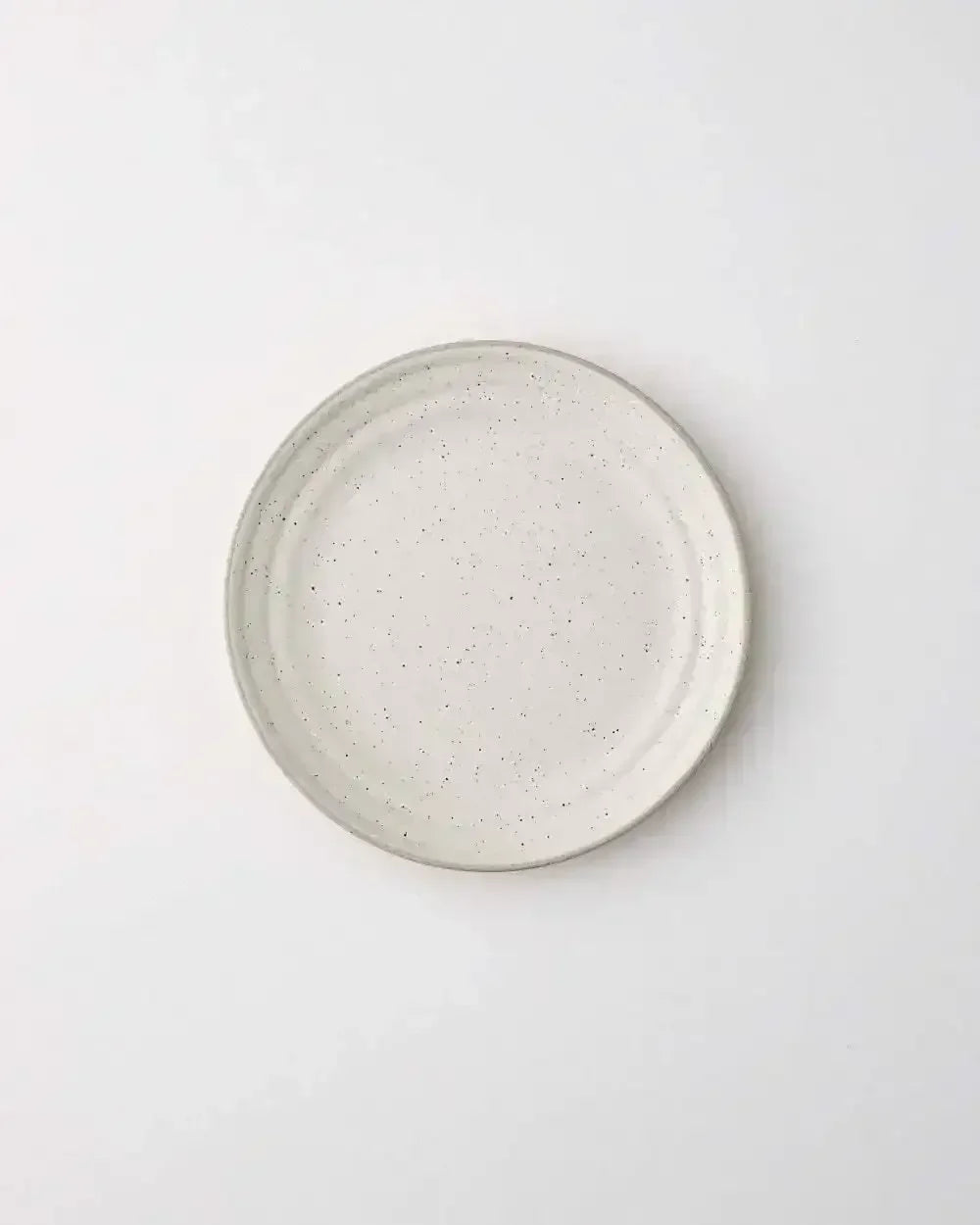 ceramic side plate with speckled glaze on white background