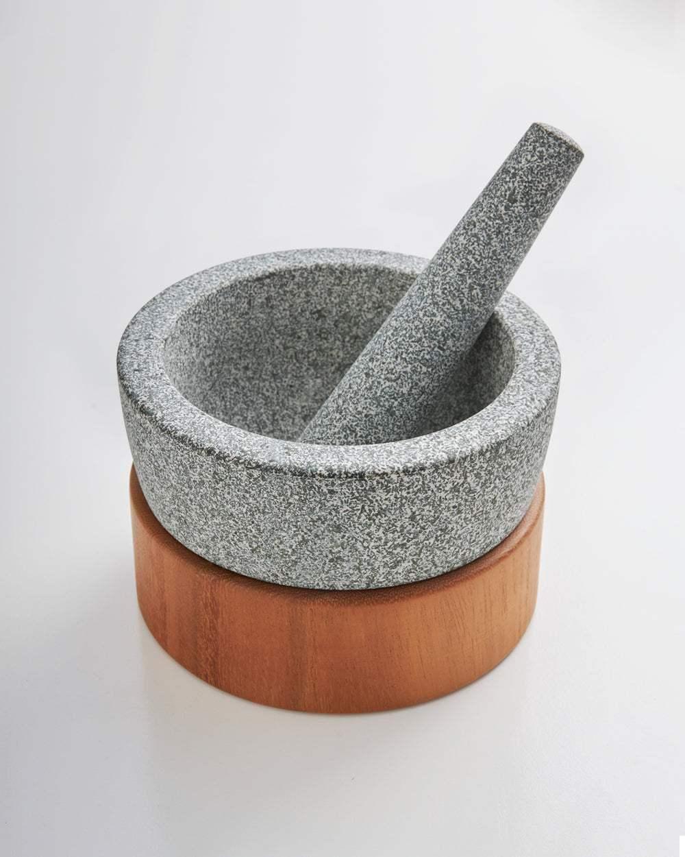 Granite mortar and pestle set with wooden base on white background
