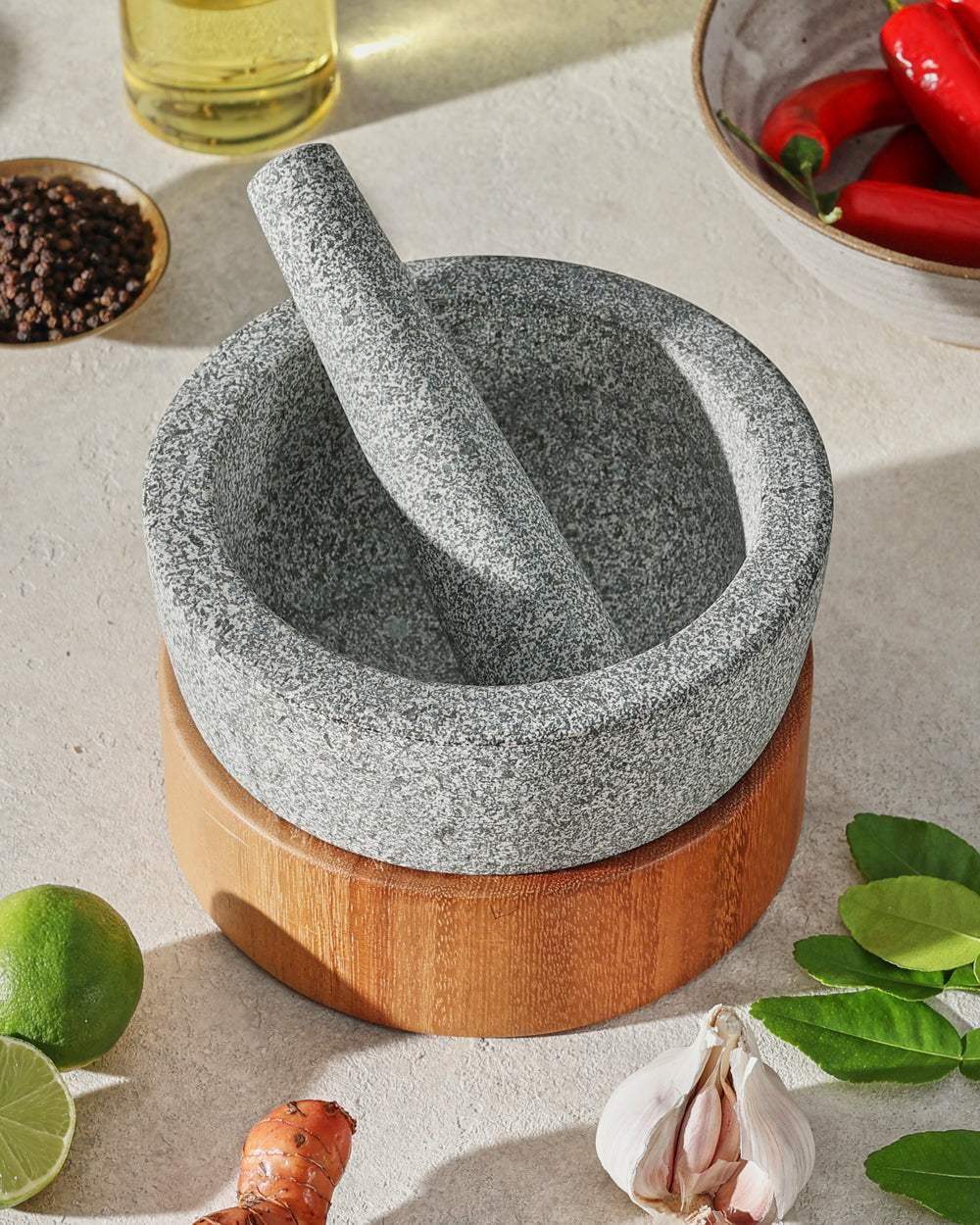 Mako granite mortar and pestle on wooden base surrounded by fresh ingredients, inspired by Marion Grasby