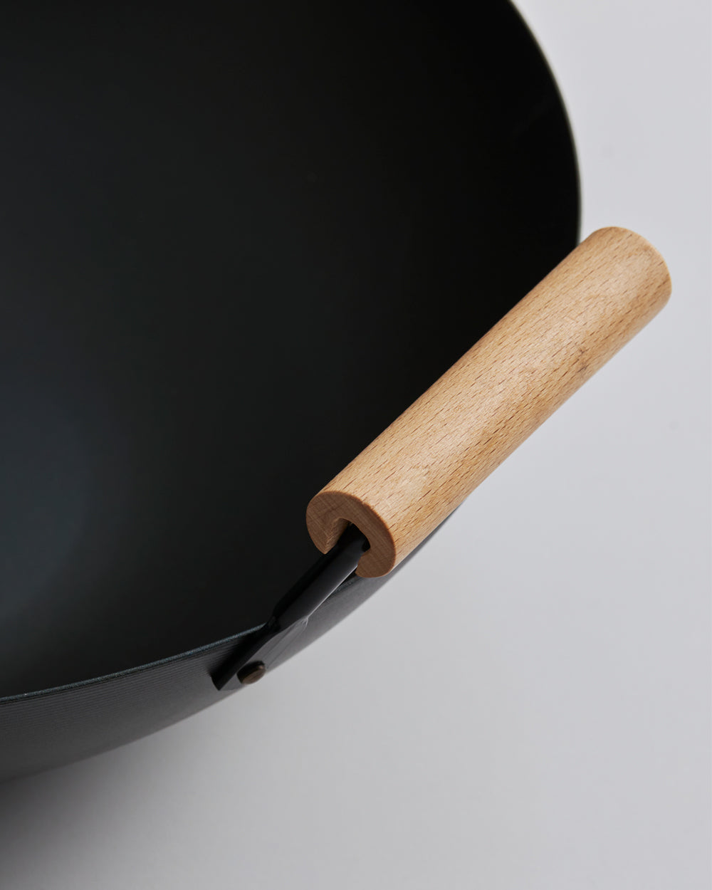 Black steel wok with wooden handle on white background, close-up cookware image