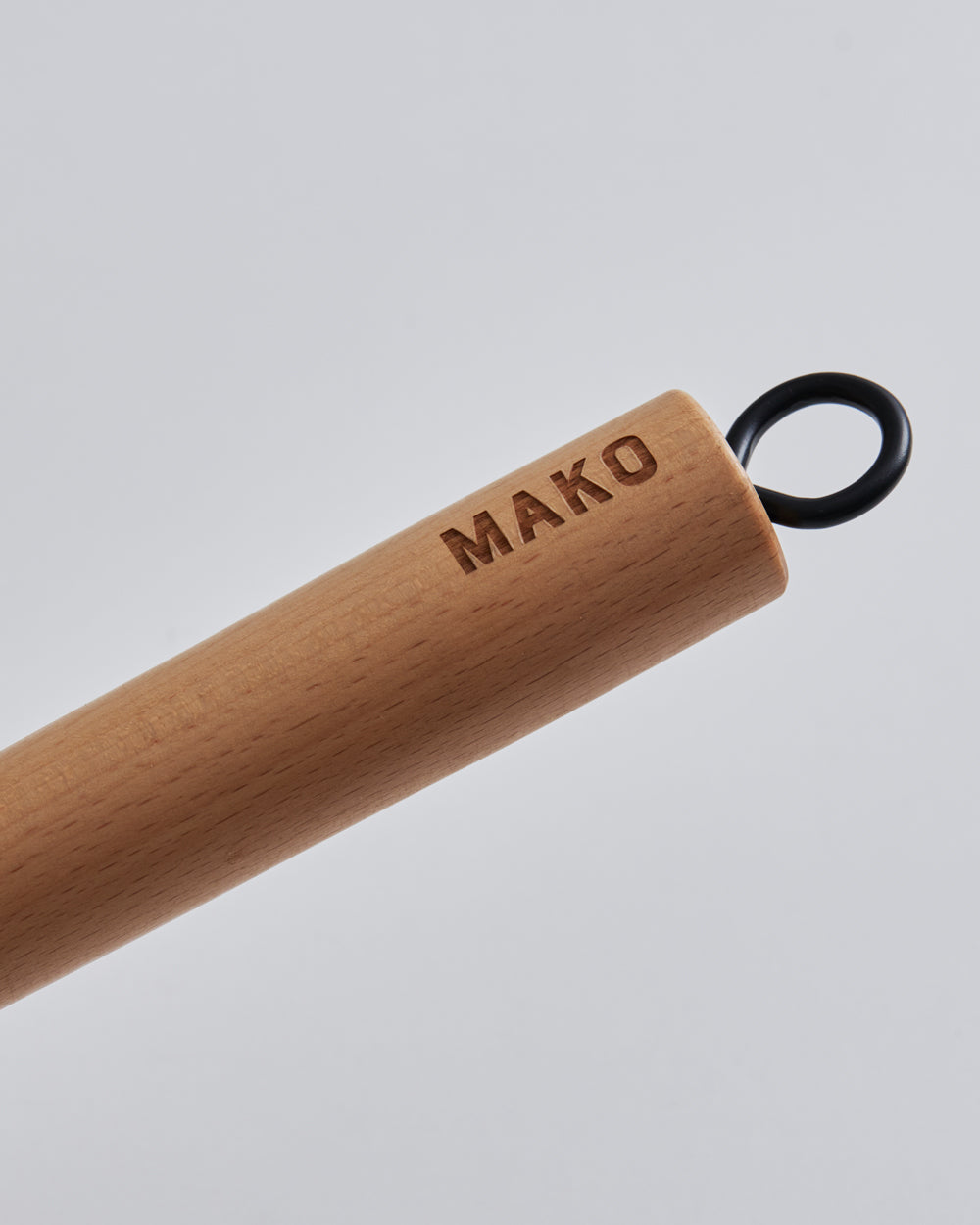 Close-up of a wooden cookware handle with MAKO engraving and a black hanging loop
