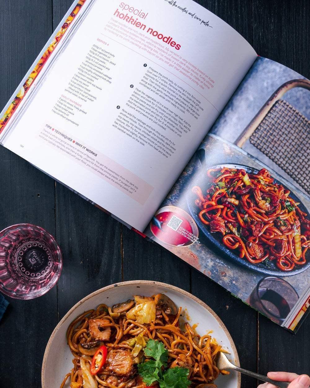 Open cookbook displaying special Hokkien noodles recipe with a plate of stir-fried noodles