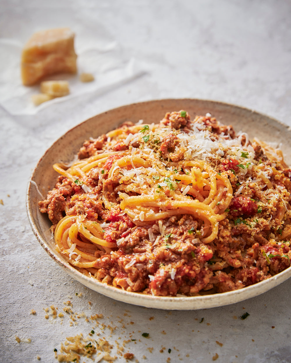 Bowl of spaghetti bolognese topped with grated parmesan cheese and herbs