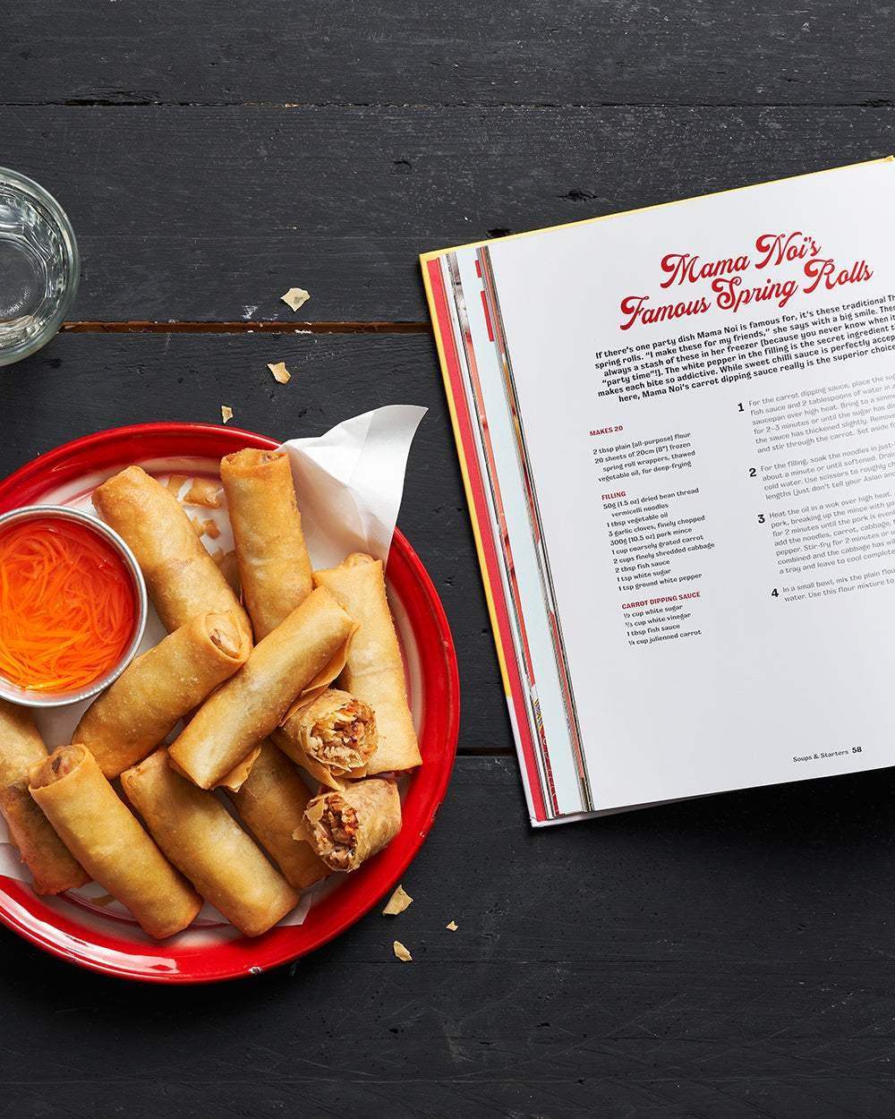 Plate of crispy spring rolls with dipping sauce beside open Asian cookbook featuring Mama Noi’s spring rolls recipe