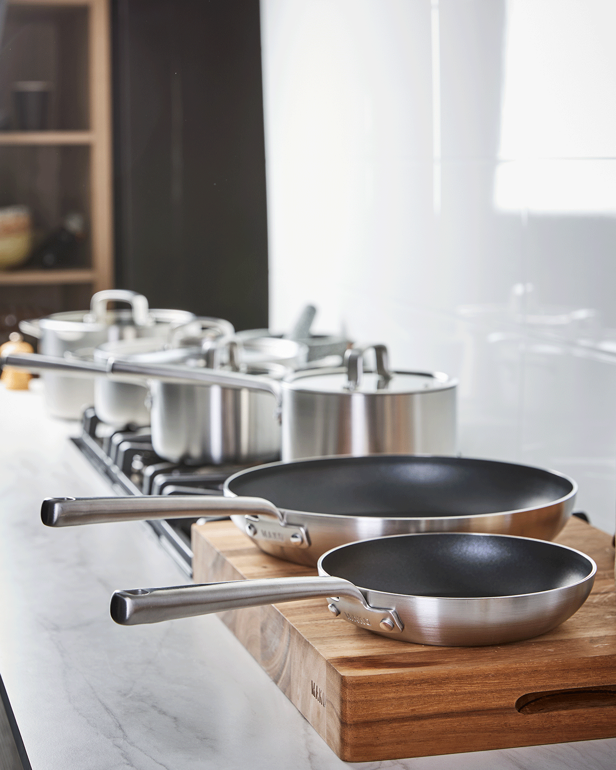 Stainless steel nonstick frying pans and saucepans on a kitchen counter and stovetop