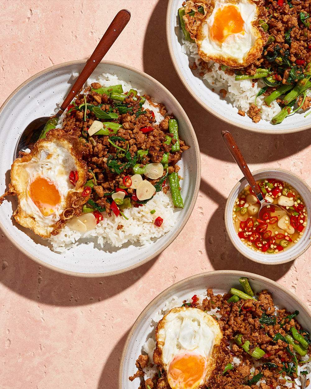 Thai basil stir fry with minced meat, rice, green beans, and crispy fried egg in bowls