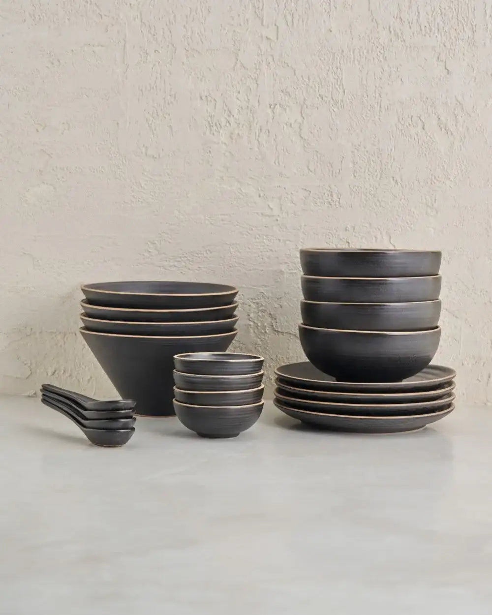 Anaya charcoal noodle lovers set featuring stacked dark matte bowls, plates, and spoons on a marble surface