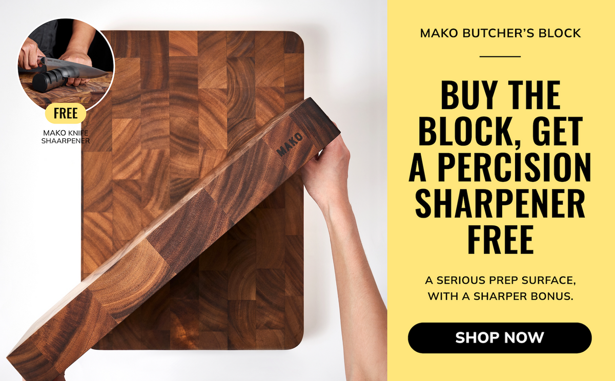 A wooden butcher block cutting board with a visible Mako logo, shown with a hand holding a sharpening block at an angle. A yellow promotional panel on the right reads 'Mako Butcher's Block' and 'Buy the block, get a precision sharpener free,' with a 'Shop Now' button.