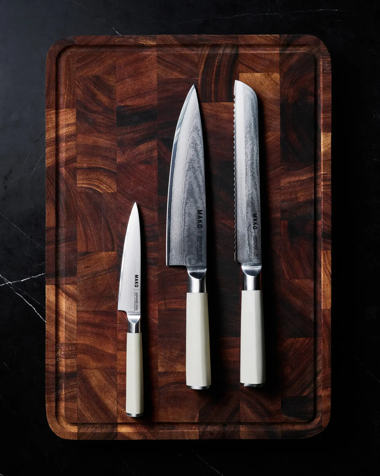 MAKO Japanese Steel Knife Trio - Cream on wooden chopping board laying on dark marble benchtop
