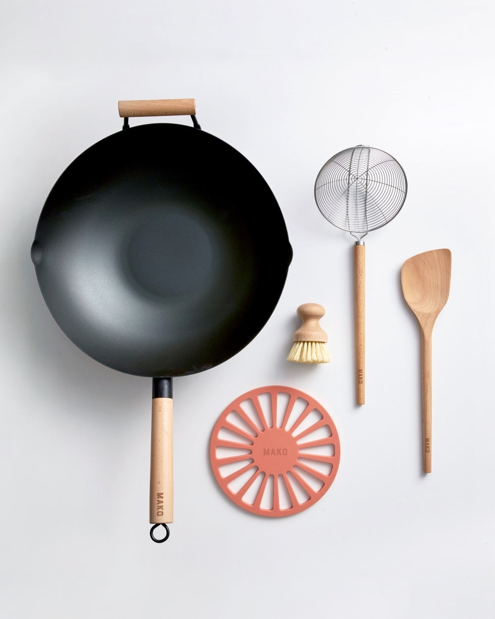 Nonstick wok with wood handle, skimmer, wooden spatula, cleaning brush, and orange trivet.