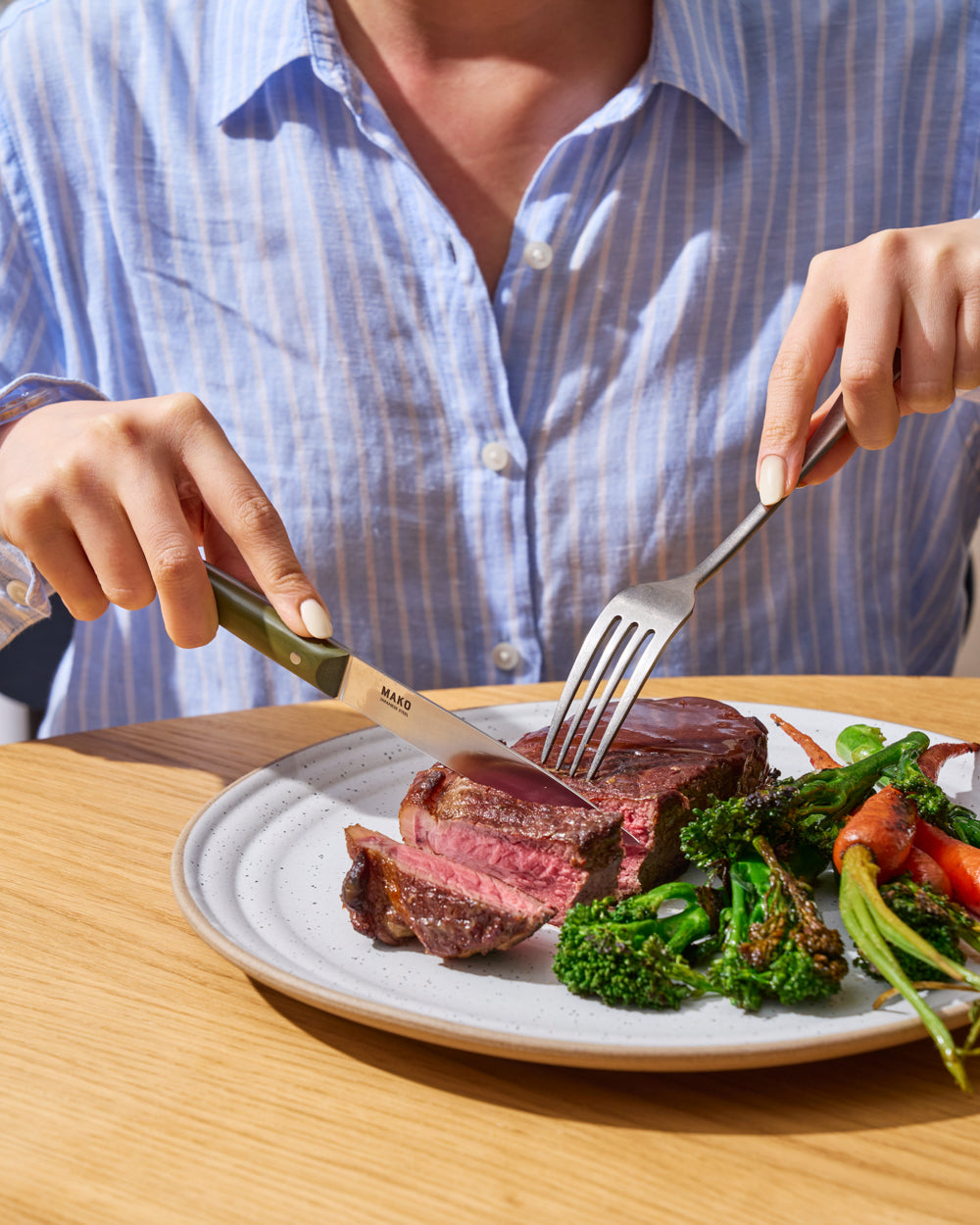 MAKO Steak Knife Set of 6 - Olive Green in use cutting steak on plate with broccoli and carrot sides blue shirt