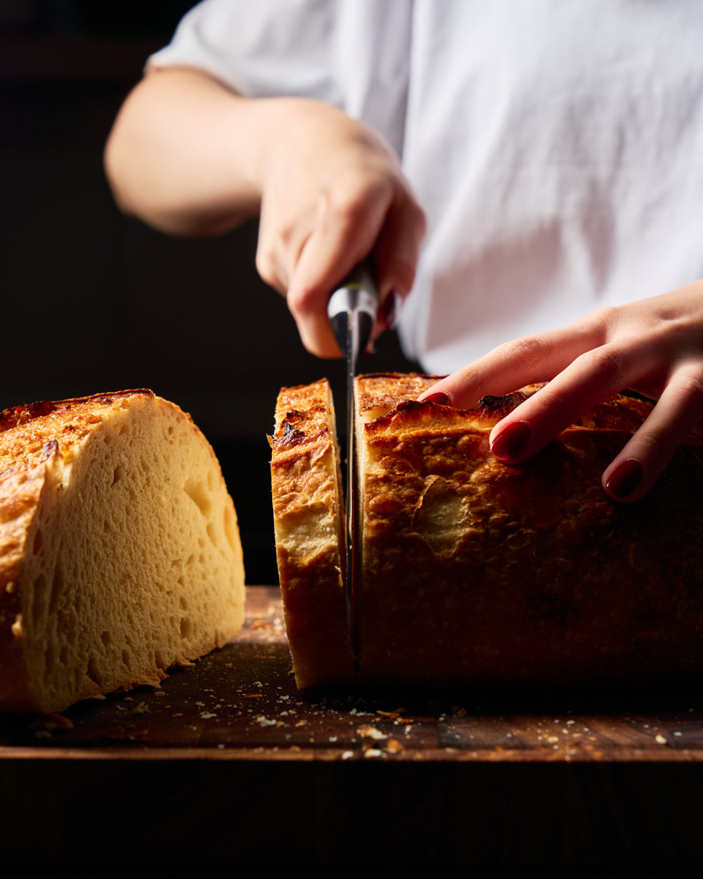 MAKO Japanese Steel Cream 8″ Bread Knife CookDineHost in use cutting thick slice of loaf on wooden chopping board