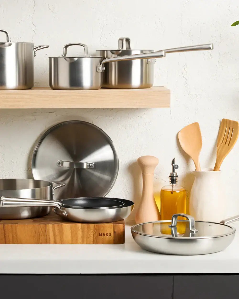 Mako stainless steel cookware set on kitchen counter with wooden utensils and oil bottle, Marion Grasby