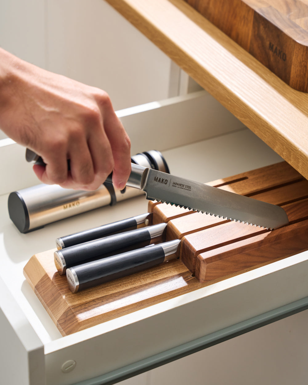 MAKO In-Drawer Knife Block bread knife being picked up out of block. Black handles in drawer