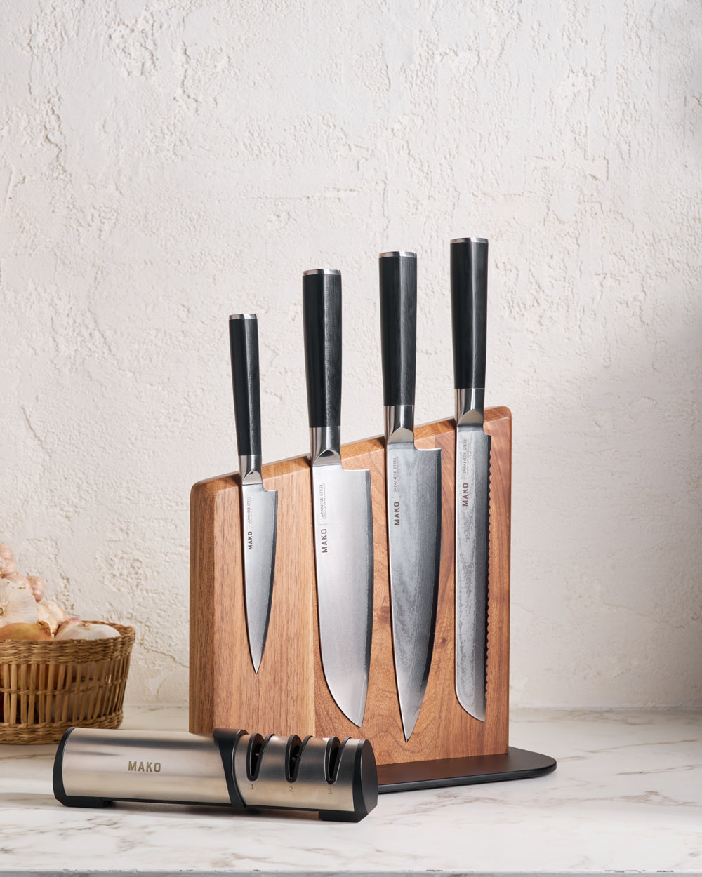 MAKO Japanese Steel Knife Set of 4 - Black Magnetic Stand on white marble benchtop with sharpener and onions garlic and ginger in cane basket to the left