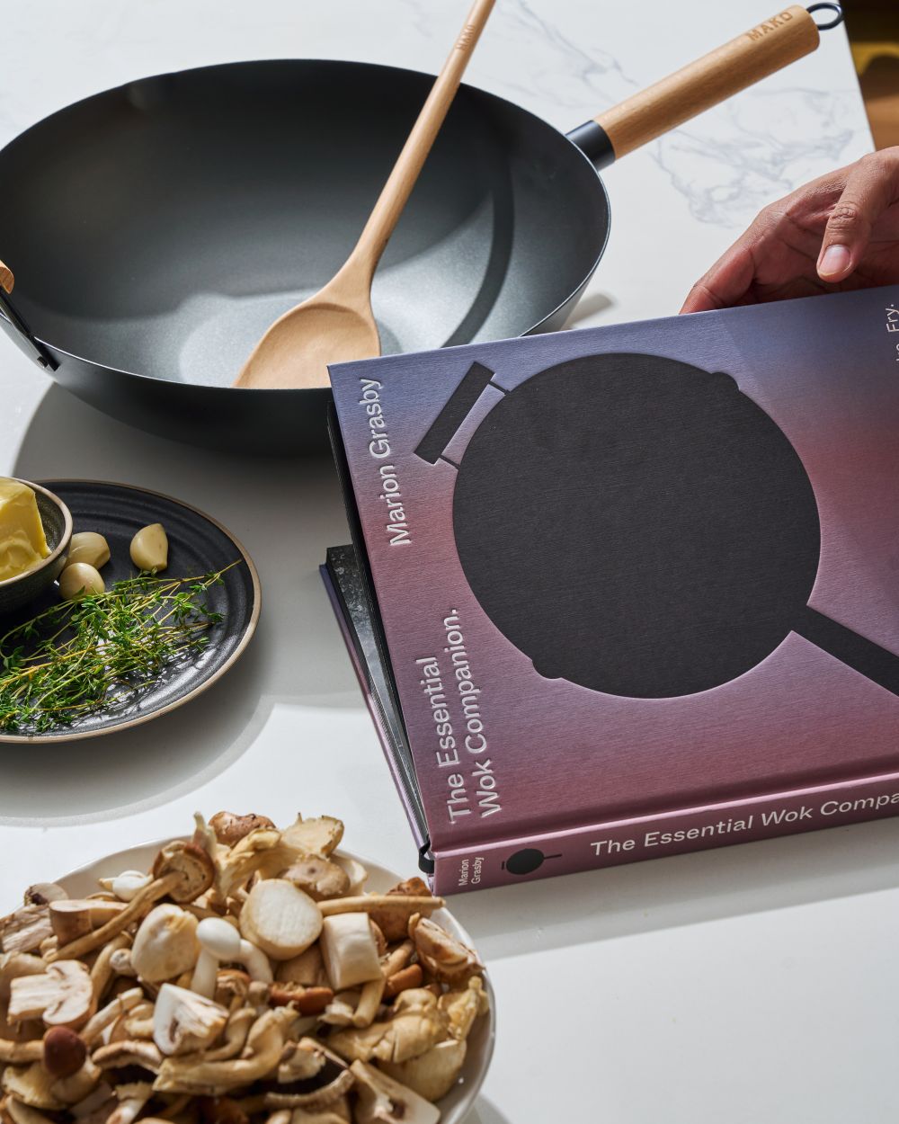 Mako Wok with companion book on table top with mushrooms thyme garlic and butter - ready to cook