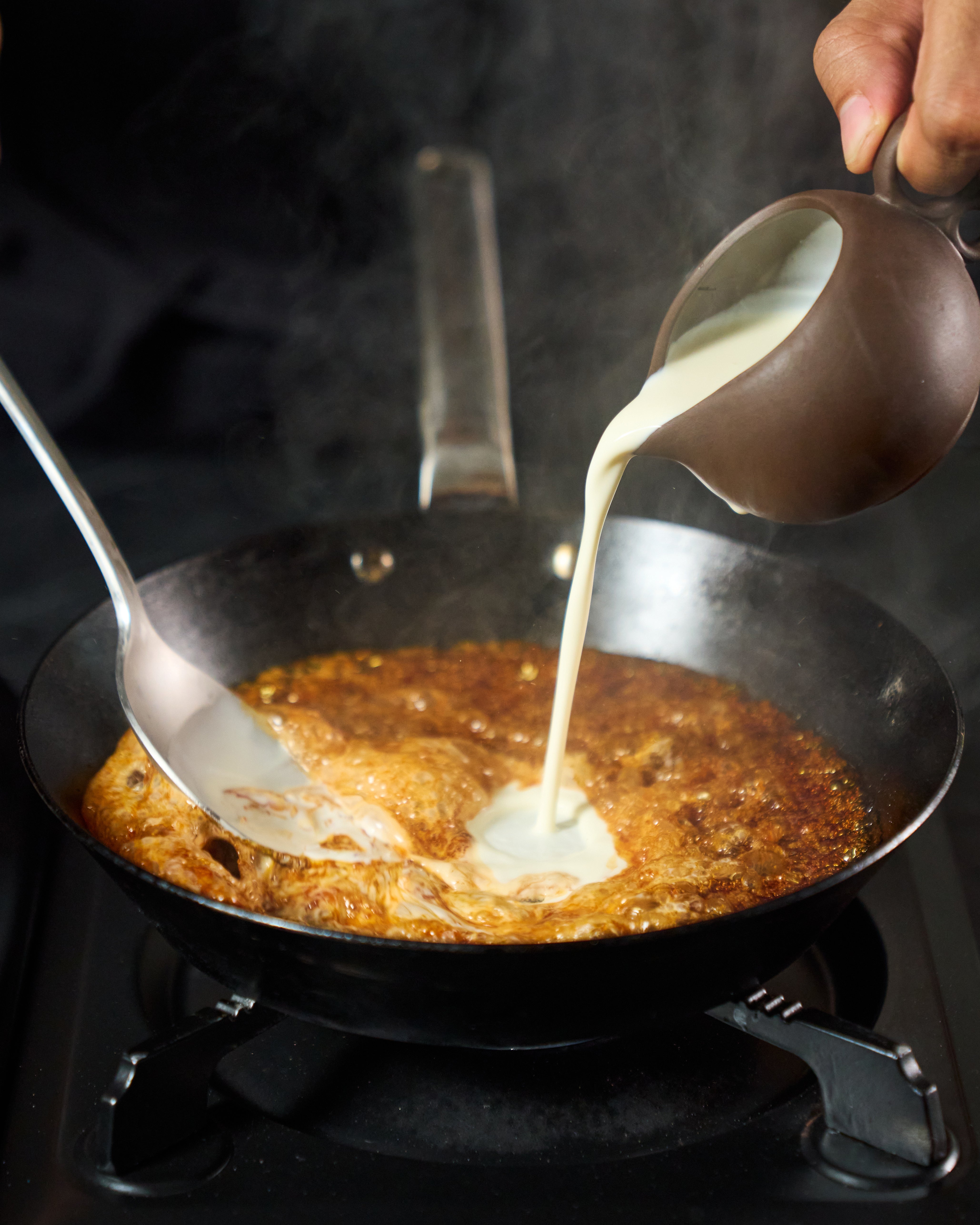 Pouring the cream and vanilla mixture into the caramel.
