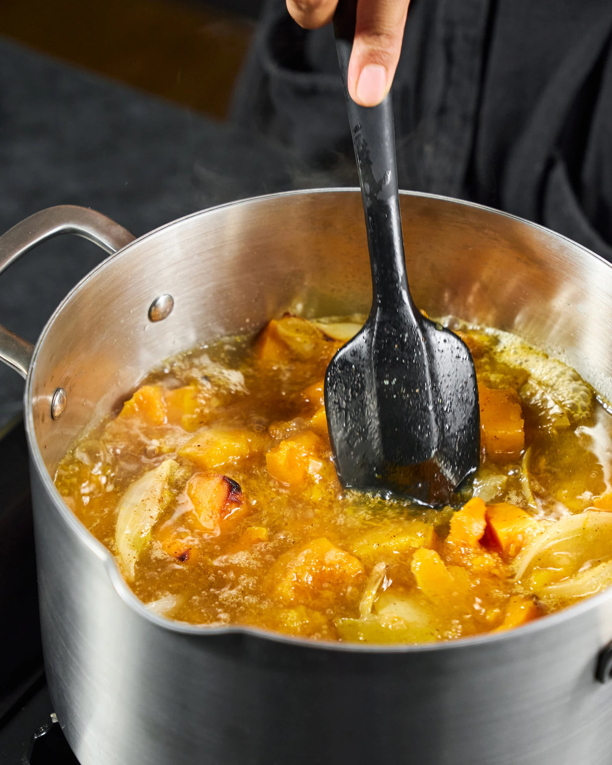 Stirring roasted pumpkin, apple and onion chunks in MAKO stainless steel stock pot with stock as the soup gently simmers.