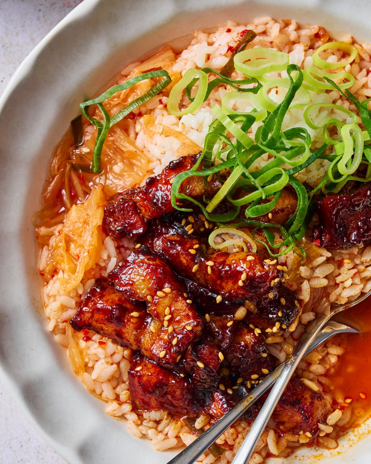 Sticky Gochujang Pork Belly with Kimchi Rice Recipe CookDineHost Close up of pork in bowl with broth and rice