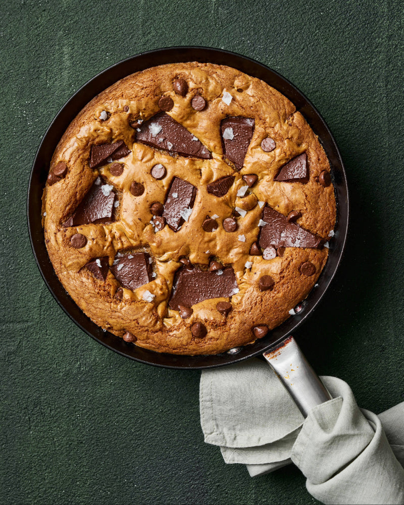 MAKO Skillet Cookie Recipe - Freshly baked chocolate chip skillet cookie, topped with chunks of dark chocolate, scattered chocolate chips, and flakes of sea salt.