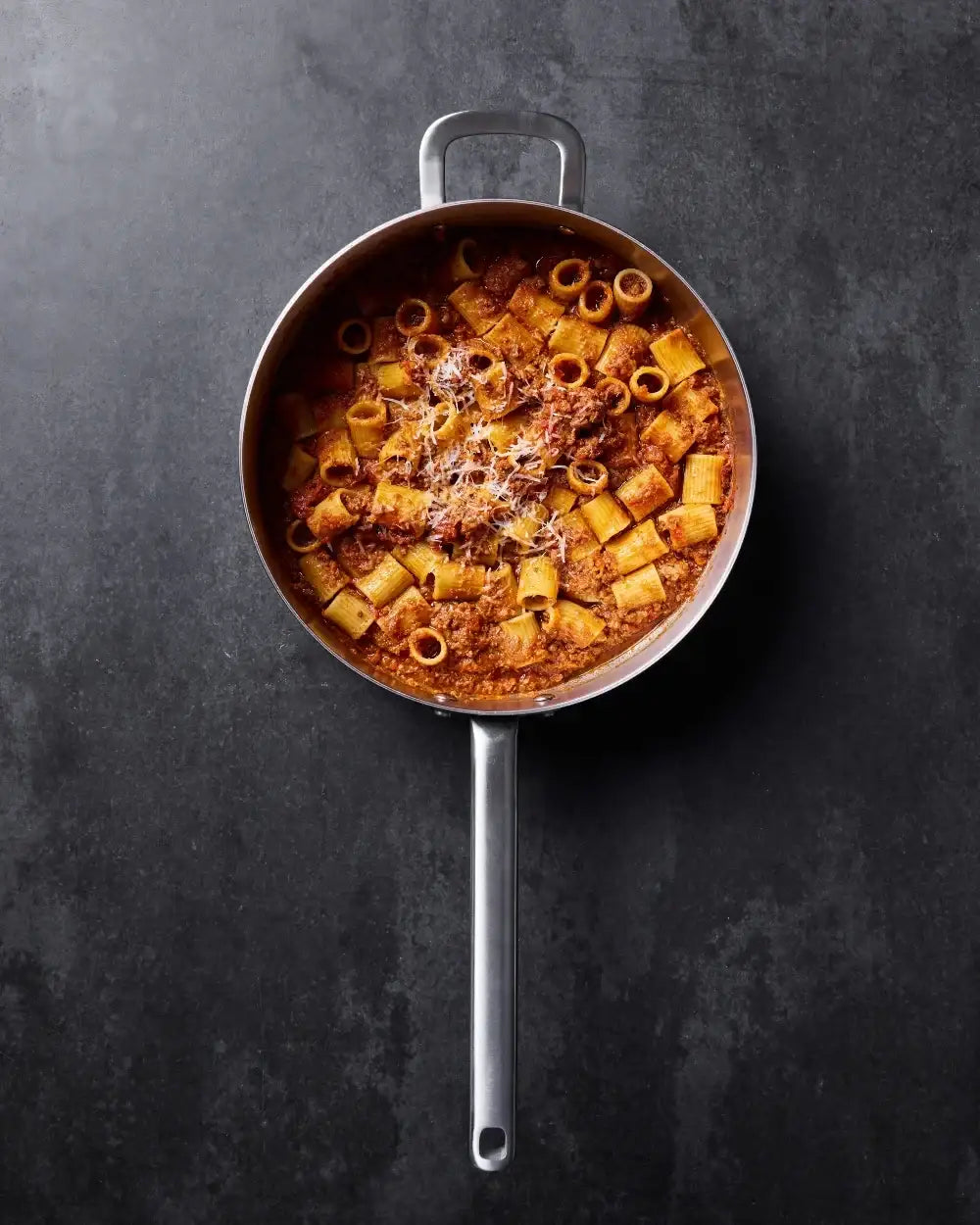 Top view of rigatoni pasta in meat sauce with grated cheese in Marion Grasby Mako saute pan