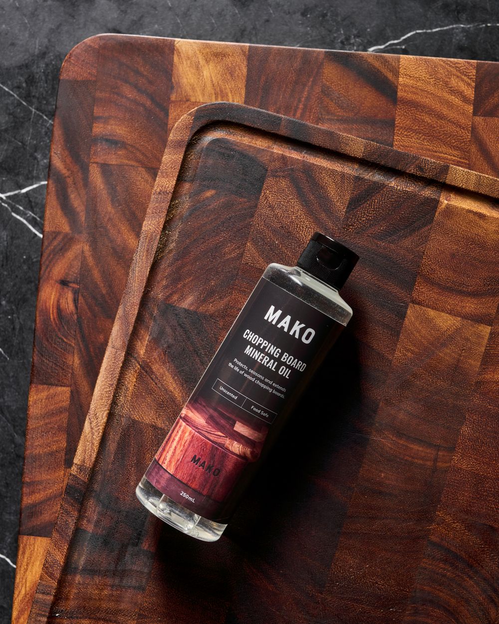 MAKO Chopping Board Mineral Oil bottle placed on top of the MAKO Master Board and Butchers Block. Black marble bench top 