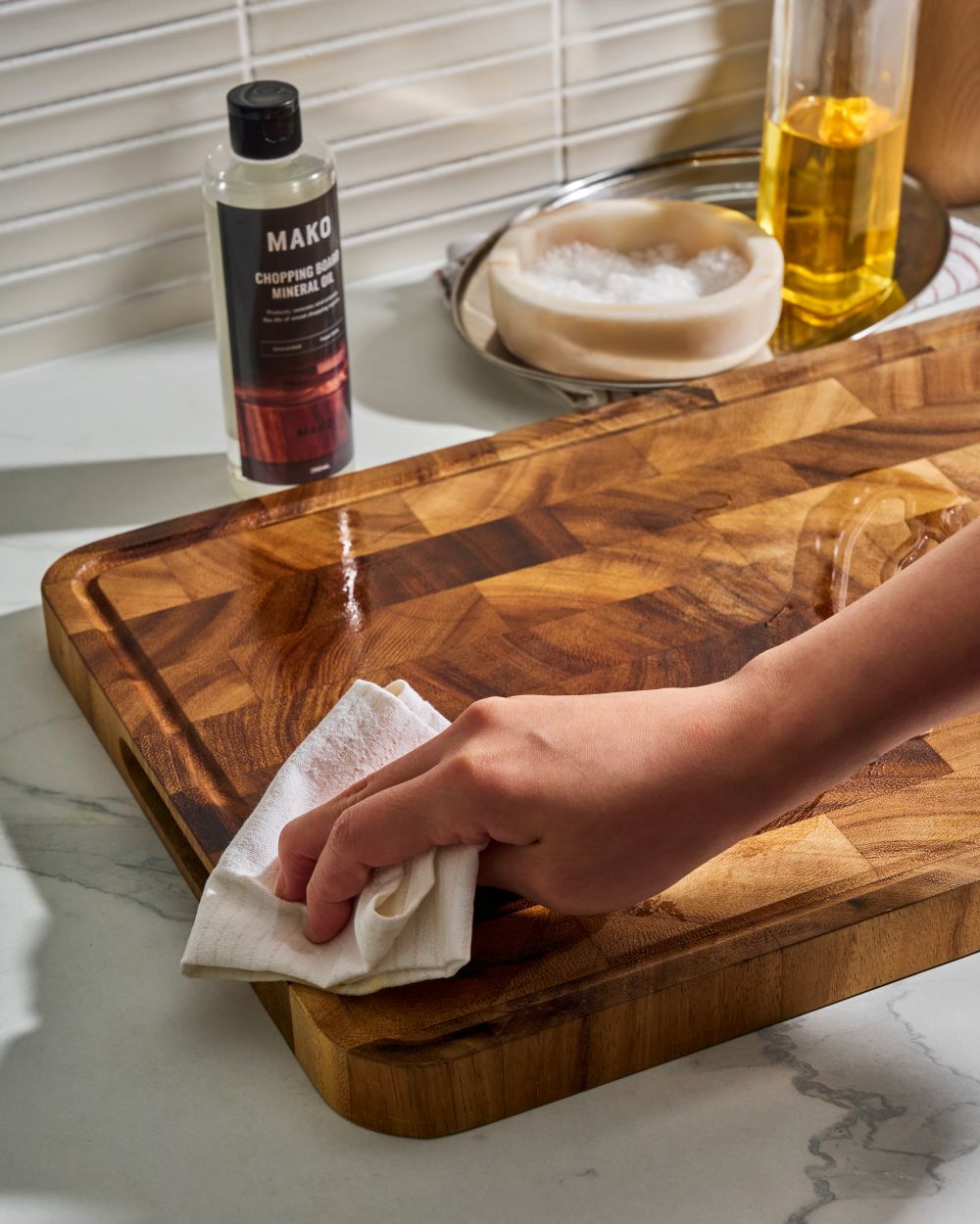 MAKO Chopping Board Mineral Oil in use on the MAKO Master Board. Rubbing in oil on board on white kitchen bench top