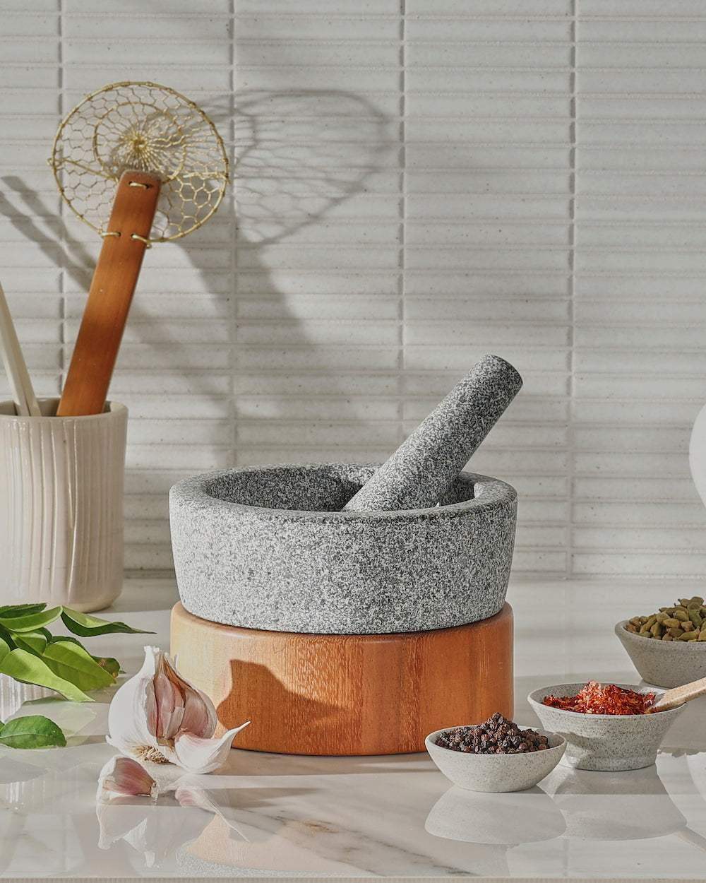 Granite mortar and pestle on kitchen benchtop with spices and garlic, modern homeware