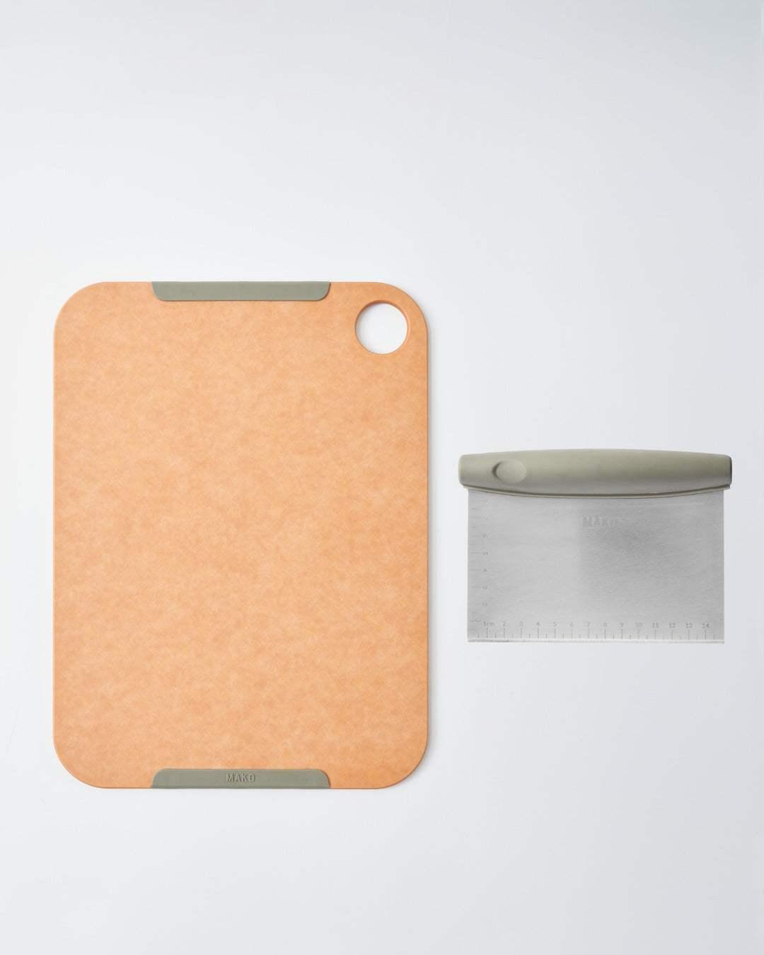 Cutting board with rubber grips and stainless steel bench scraper on white background