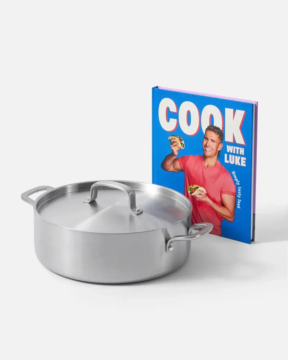 Stainless steel lidded pan beside Cook with Luke cookbook featuring man in red shirt holding tacos