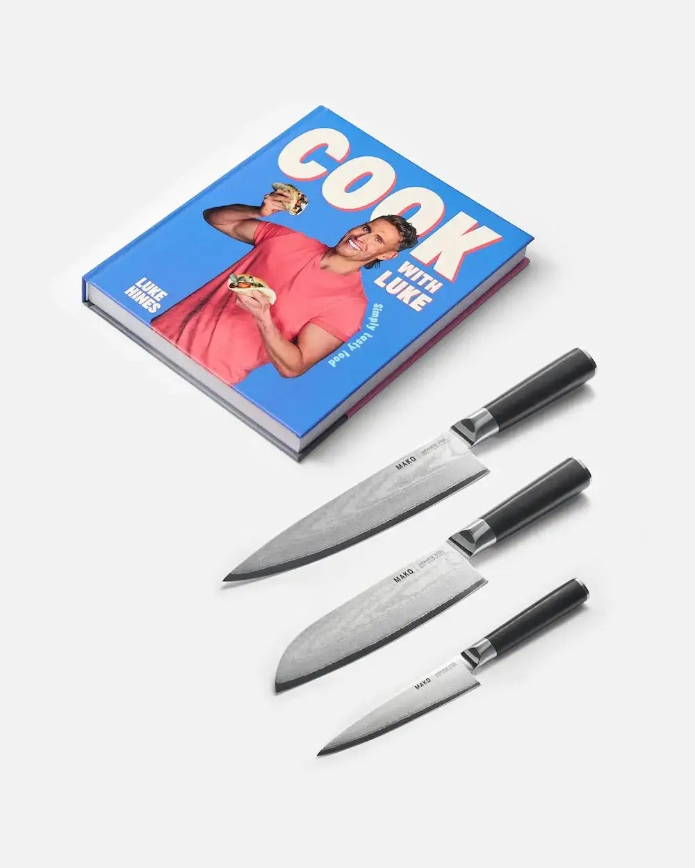 Cookbook "Cook with Luke" by Luke Hines and a set of three Mako kitchen knives with black handles on white background