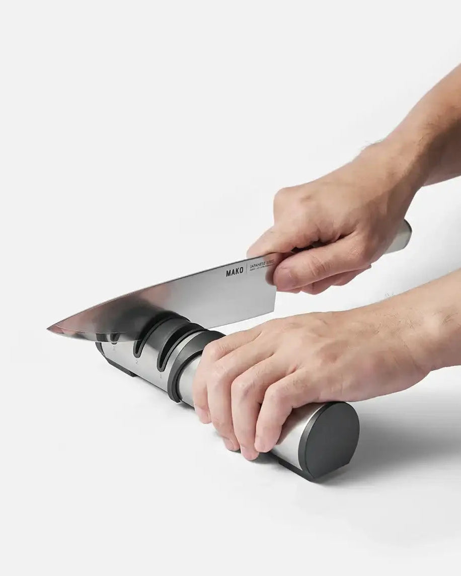 Hands sharpening a Mako Japanese steel knife on a stainless steel knife sharpener