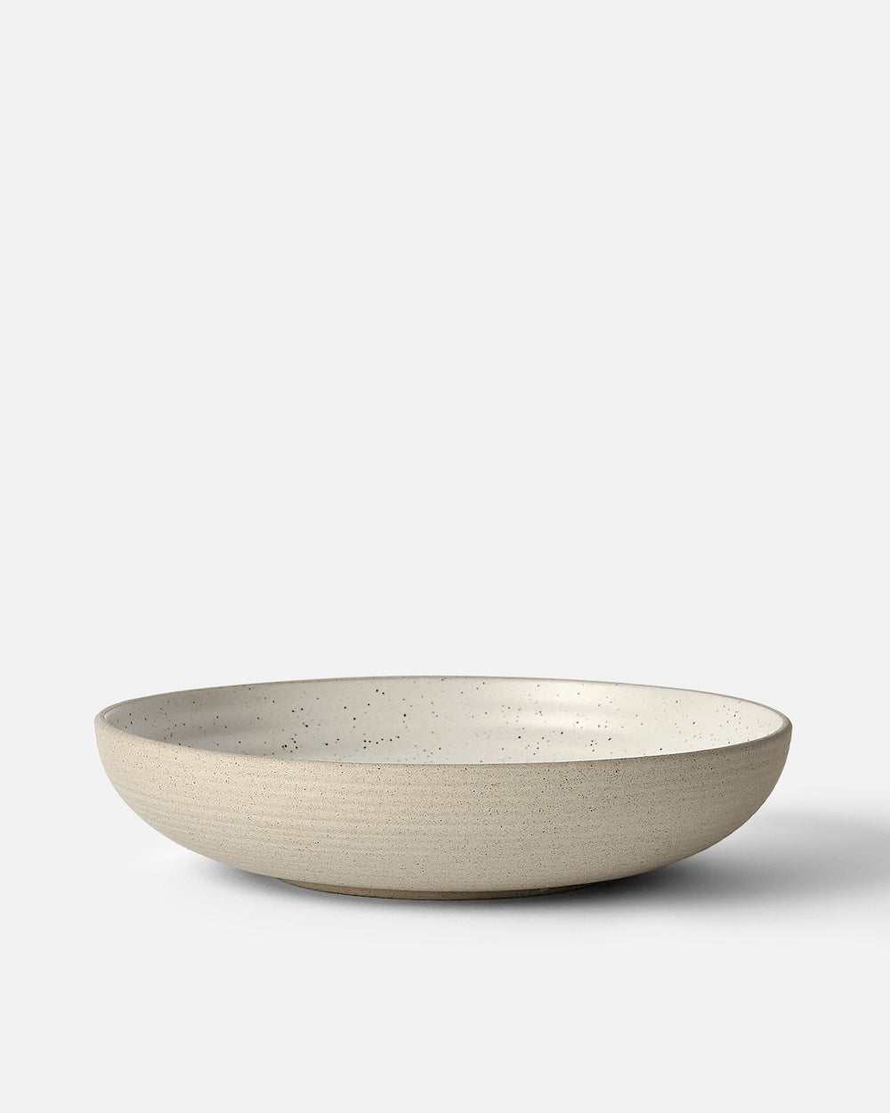 Wide shallow stoneware bowl with matte beige exterior and speckled white interior