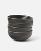 Stack of four black Asoke ceramic cereal bowls by Marion Grasby on white background