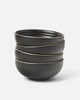Stack of four black Asoke ceramic cereal bowls by Marion Grasby on white background