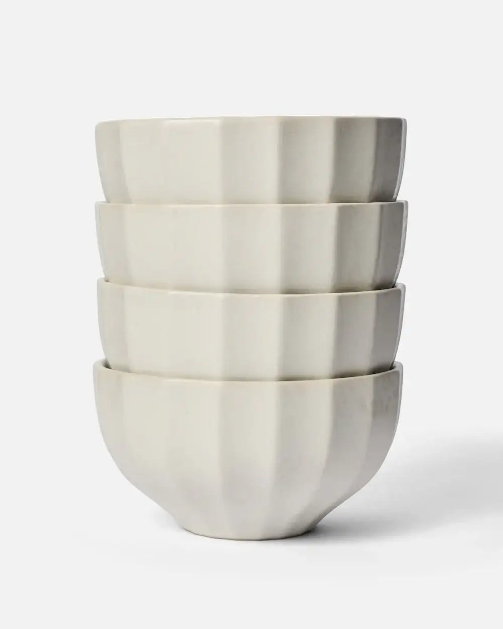 Stack of four cream-colored ceramic noodle bowls with a fluted design by Marion Grasby