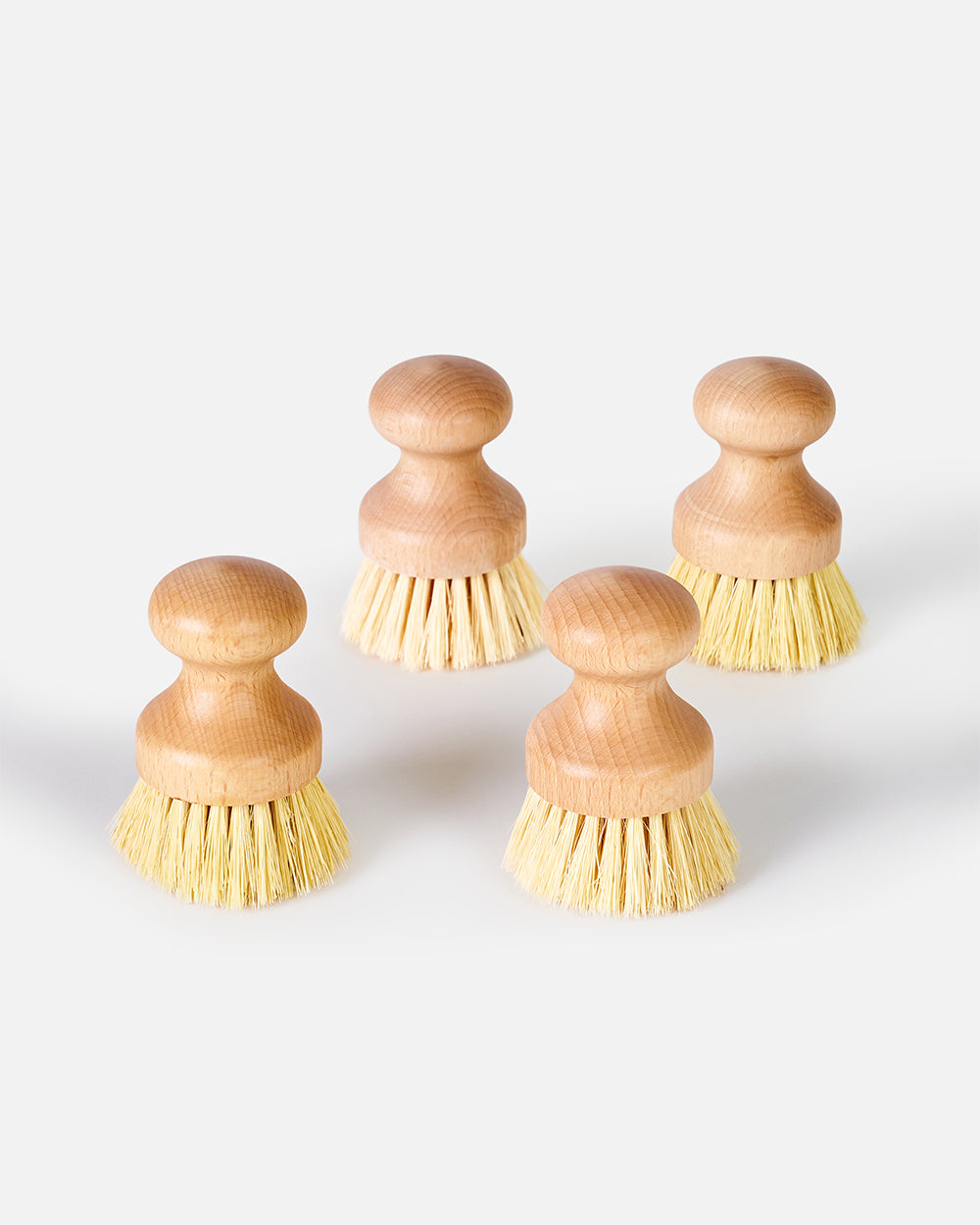 Set of four wooden kitchen scrub brushes with natural bristles on a white background