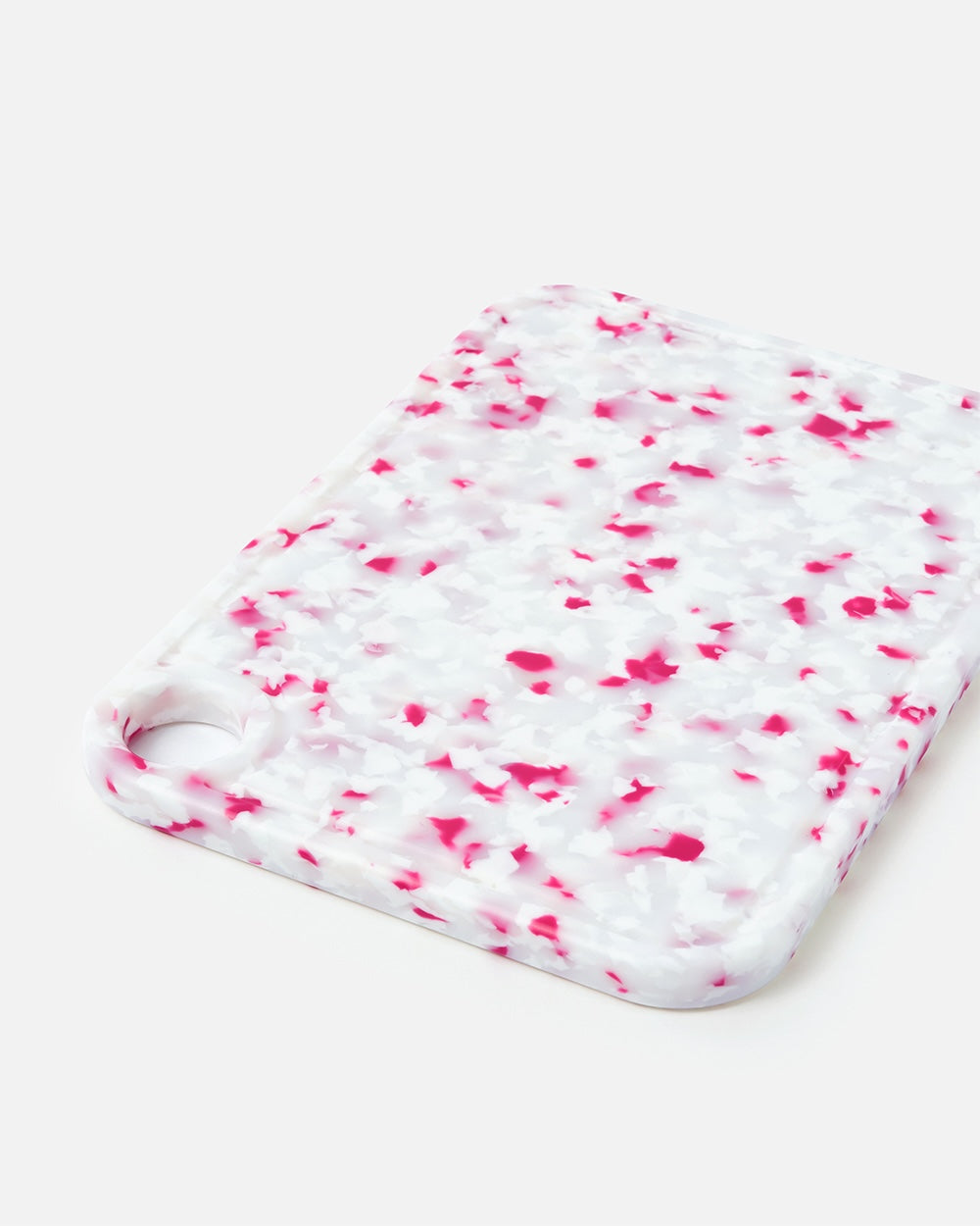 White and pink terrazzo cutting board with rounded edges on a plain background