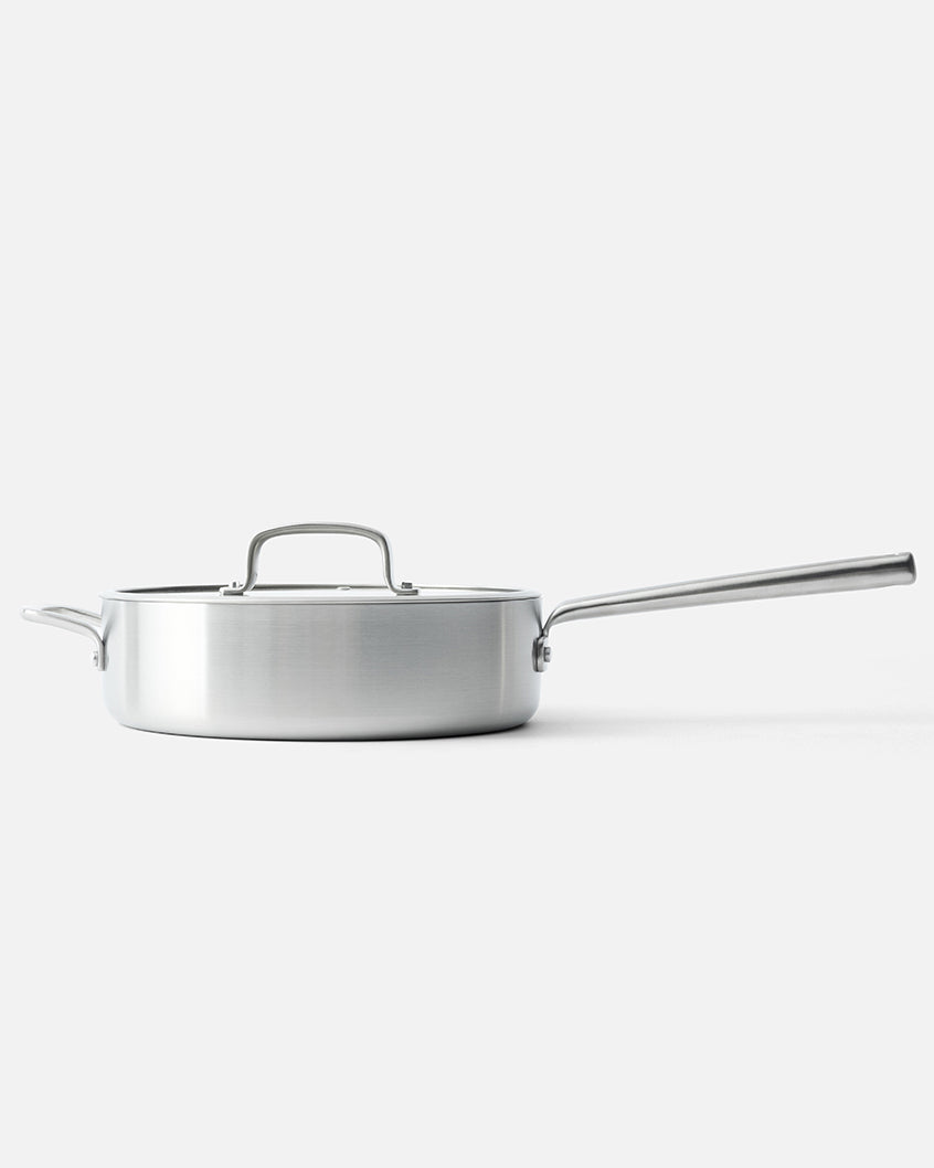 Stainless steel sauté pan with lid and long handle on a white background