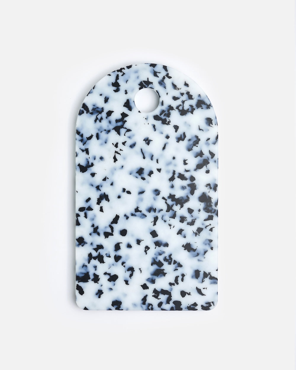Speckled white and black rectangular cutting board with rounded top and handle hole