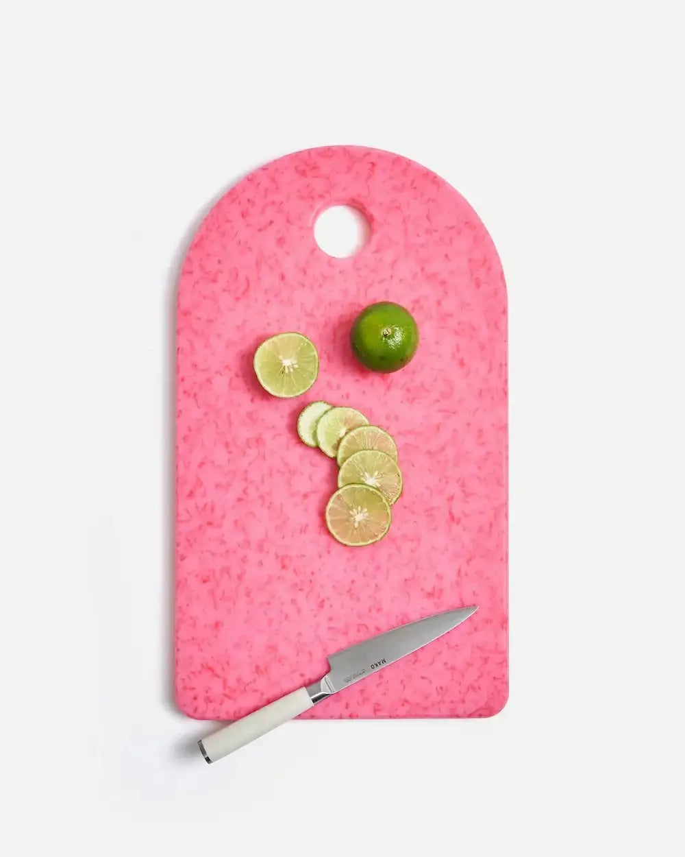 Pink Mako cutting board by Marion Grasby with sliced green lime and white-handled kitchen knife