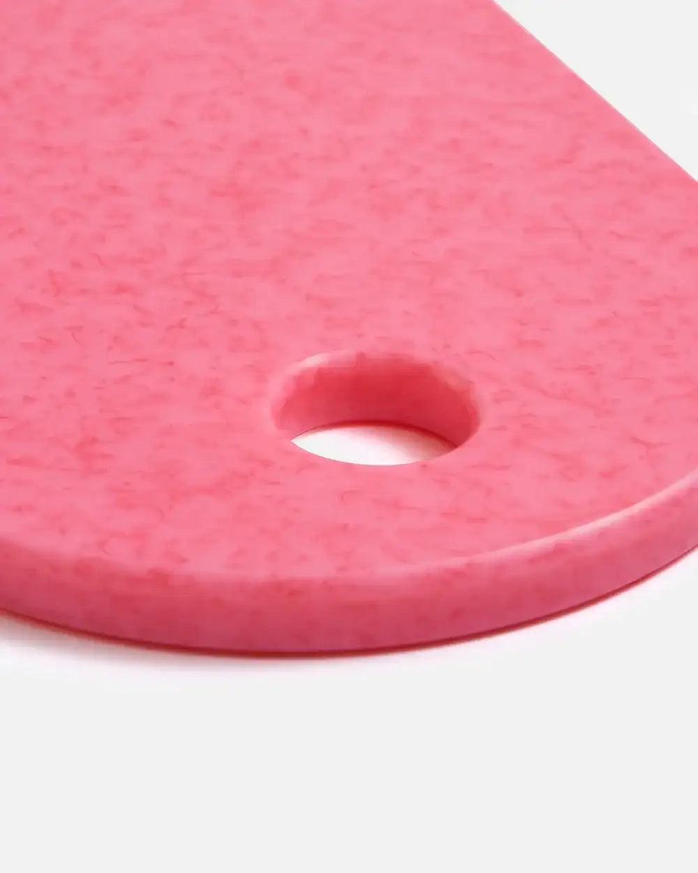 Close-up of pink marbled kitchen cutting board with round hanging hole by Marion Grasby