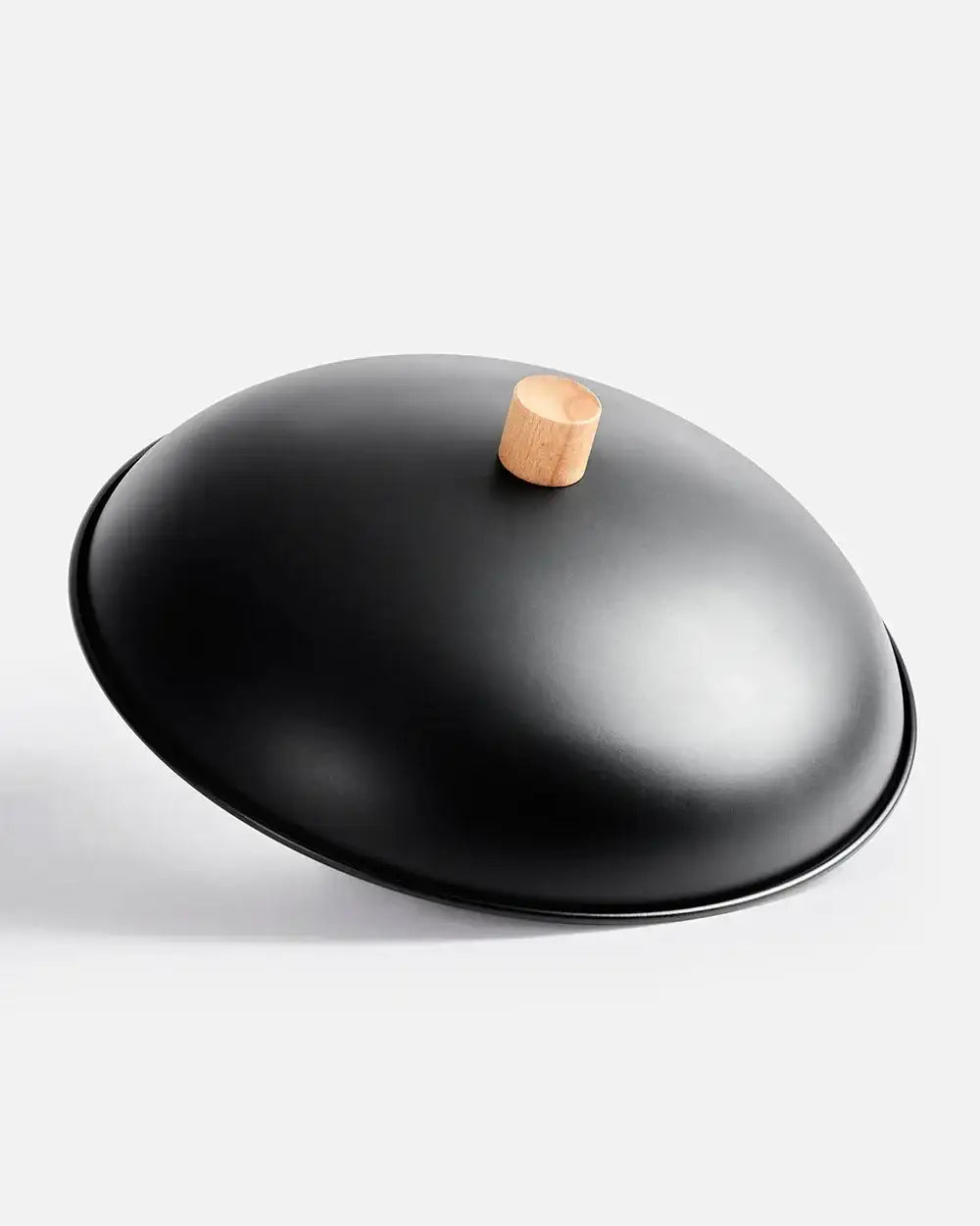 Black wok lid with wooden knob handle on white background, kitchen cookware by Marion Grasby