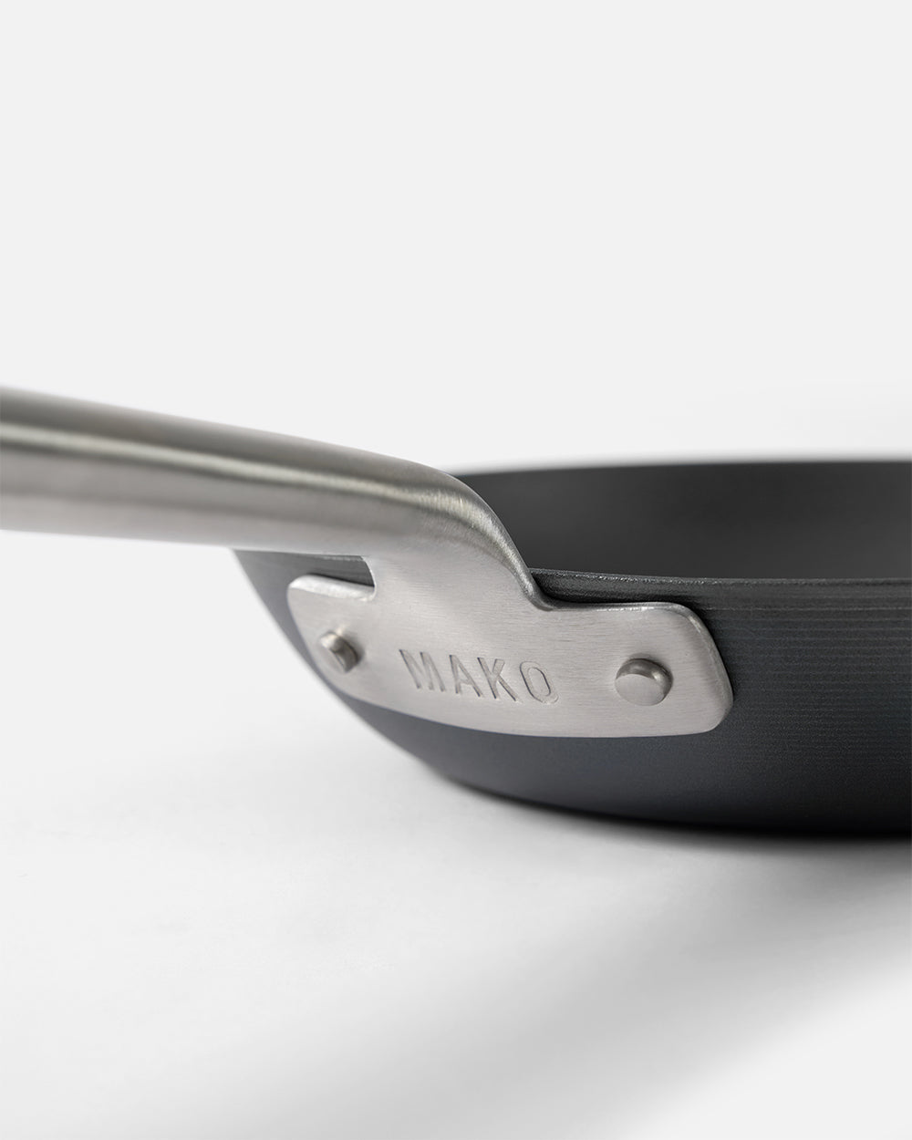 Close-up of a black steel frying pan with stainless steel handle on white background