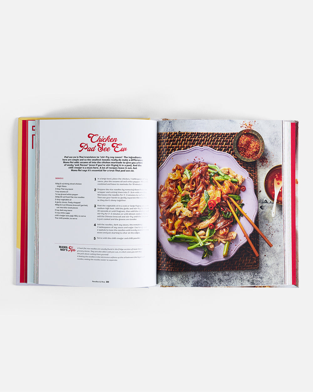Open cookbook showing chicken pad see ew recipe with plated noodle dish and chopsticks