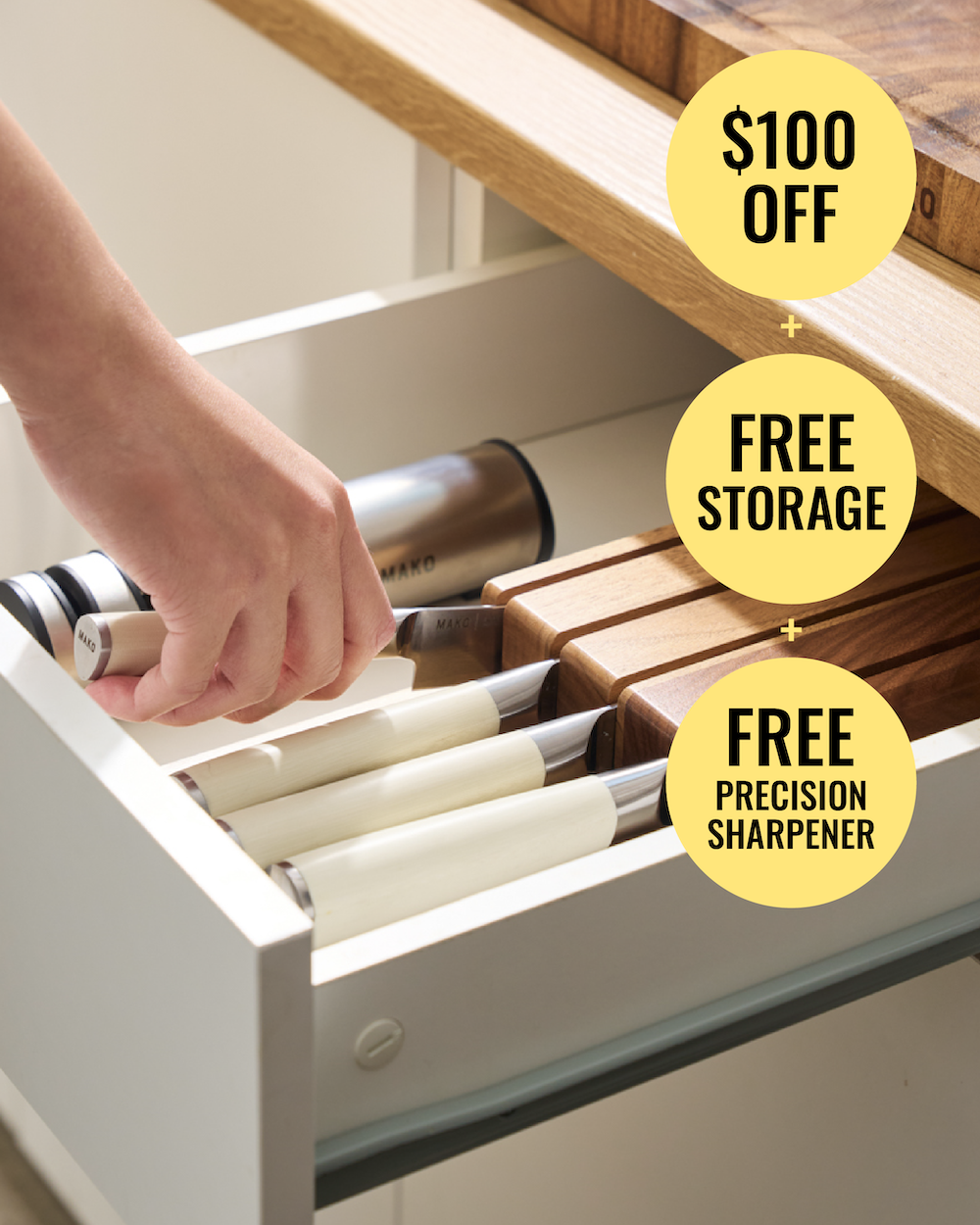 A hand opens a white kitchen drawer containing several knives with cream-colored handles and wooden blades. Yellow promotional text bubbles read '$100 OFF', 'FREE STORAGE', and 'FREE PRECISION SHARPENER'.