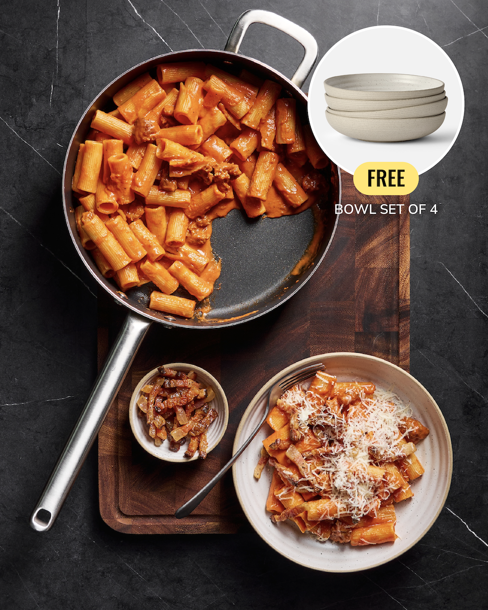 A stainless steel skillet filled with pasta and meat sits on a dark stone surface, with a plated serving of pasta and a small bowl of sauce nearby. A circular inset shows a set of four light beige bowls, with text reading 'FREE BOWL SET OF 4'.