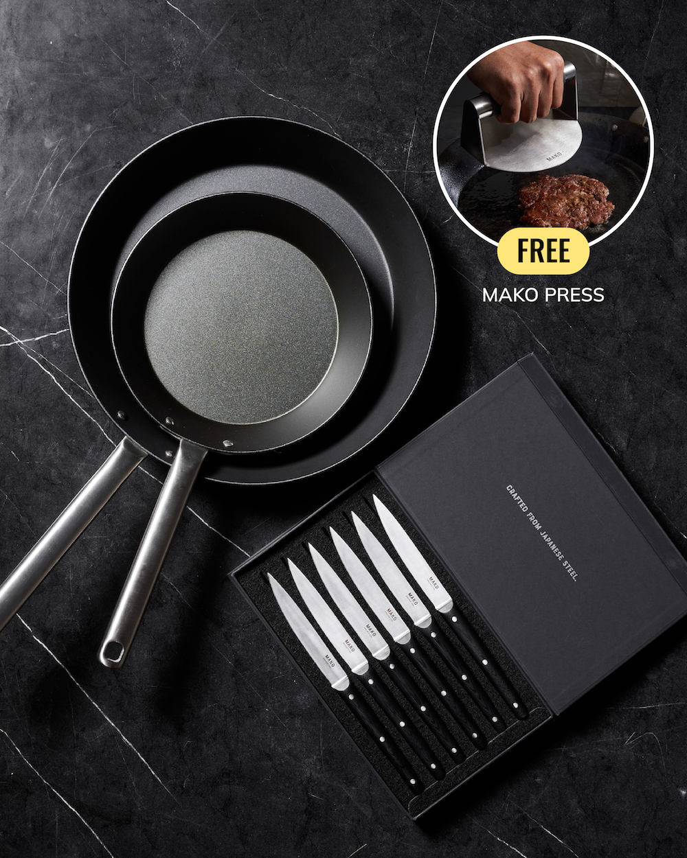 A cookware set on a dark marble-style background, featuring two black frying pans, a boxed set of six steak knives with black handles and silver blades, and a circular inset showing a hand using a Mako Press to press a burger. The main product appears to be the cookware and knife set, with the inset promoting a free accessory.